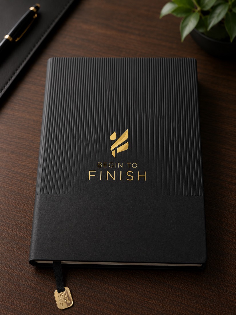 The Begin to FINISH journal — black cover with gold-embossed Begin to FINISH branding and a gold ribbon marker