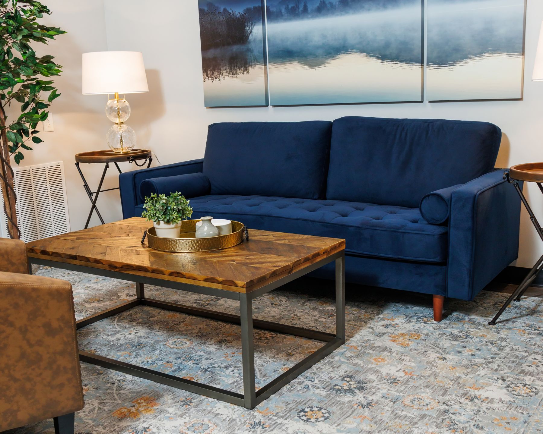 The FINISH lounge in Athens: a navy sofa beneath a misty mountain triptych; warm wood and calm, not a waiting room